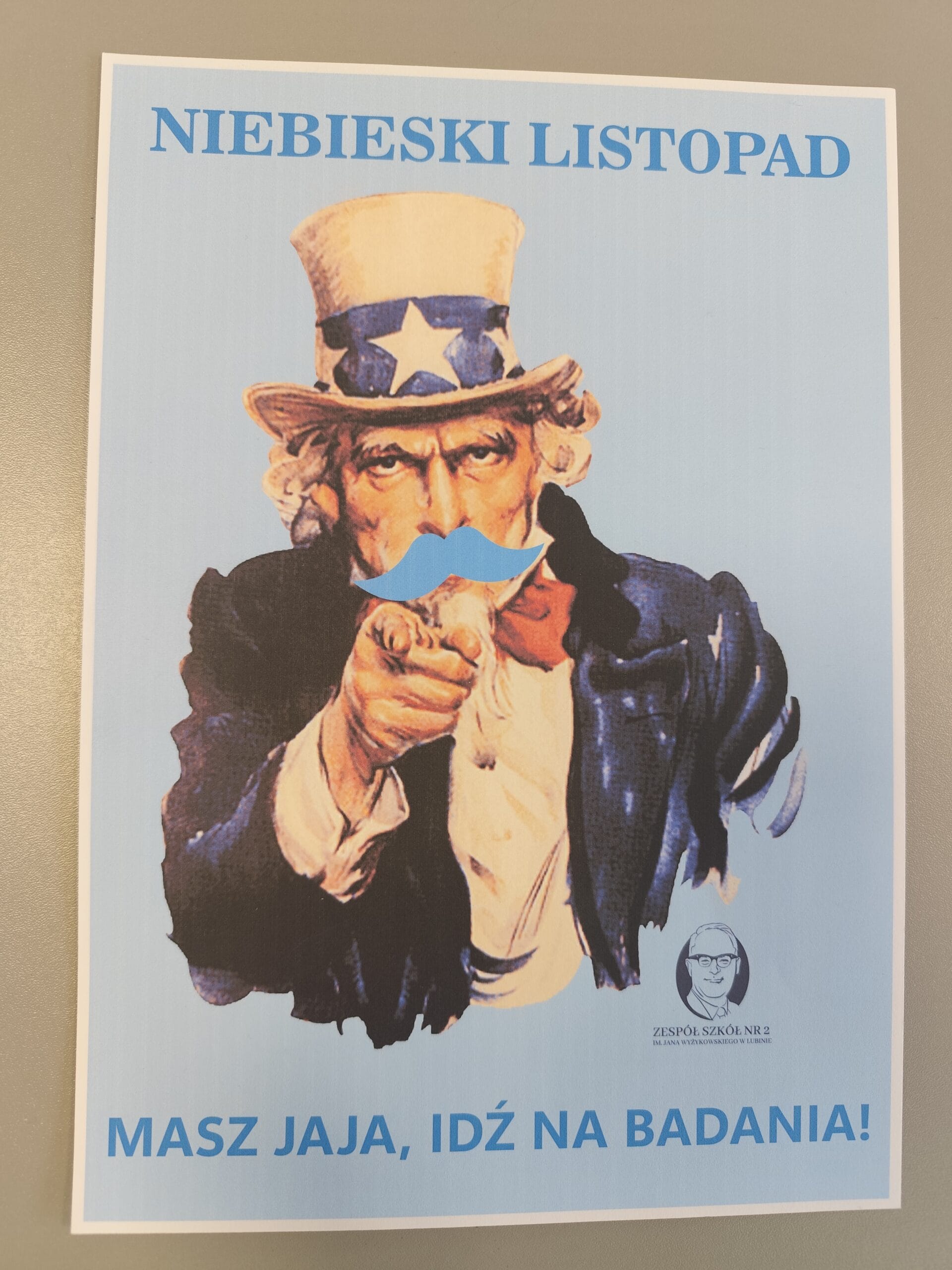 Plakat kampanii zdrowotnej z ilustracją w stylu Uncle Sam, wskazującą palcem w stronę odbiorcy. U góry napis: ‘NIEBIESKI LISTOPAD’. Na dole napis: ‘MASZ JAJA, IDŹ NA BADANIA!’. W prawym dolnym rogu znajduje się logo Zespołu Szkół