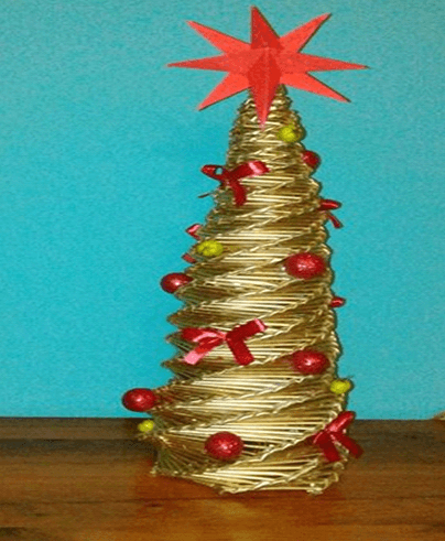 Ręcznie wykonana choinka świąteczna z plecionych złotych pasków papieru lub wikliny, ozdobiona czerwonymi kokardkami, czerwonymi i zielonymi kulkami. Na czubku znajduje się duża czerwona gwiazda. Tło jest niebieskie, a choinka stoi na drewnianej powierzchni
