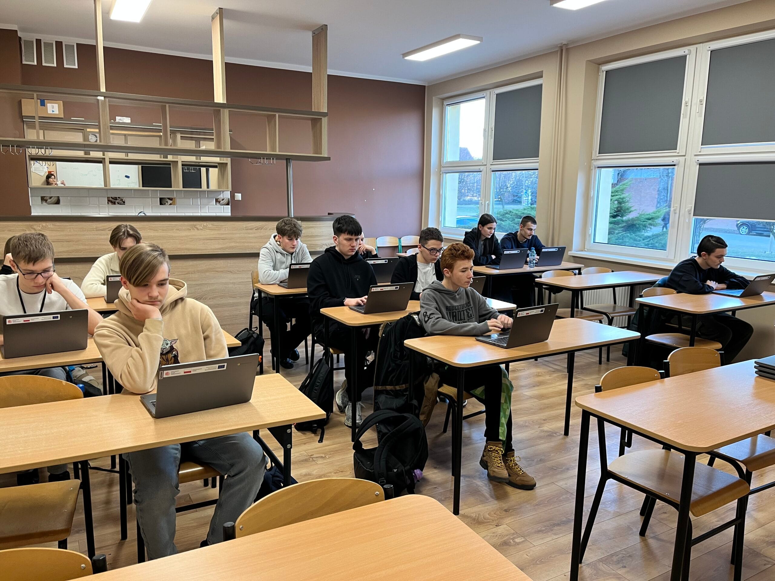 Uczniowie pracują na laptopach podczas lekcji w szkolnej klasie