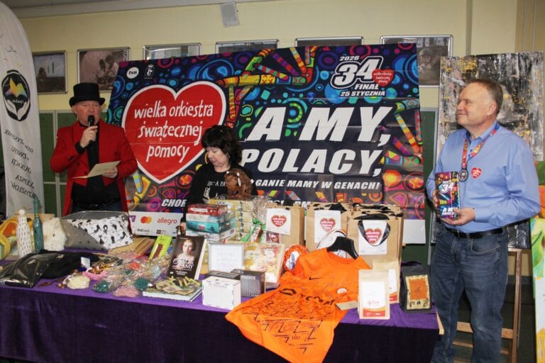 Stoisko szkolne z fantami przygotowanymi na finał Wielkiej Orkiestry Świątecznej Pomocy, z prowadzącymi prezentującymi przedmioty do licytacji