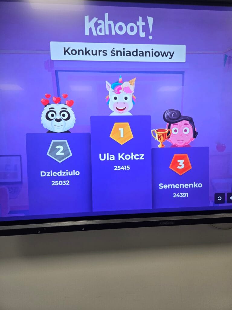 Zdjęcie ekranu z wynikami quizu Kahoot zatytułowanego „Konkurs śniadaniowy”. Na podium znajdują się trzej zwycięzcy: 1. miejsce zajęła Ula Kołcz (25415 pkt), 2. miejsce Dziedziulo (25032 pkt), a 3. miejsce Semenenko (24391 pkt). Każdemu profilowi towarzyszy animowany awatar (jednorożec, panda z sercami i postać w stylu Elvisa).