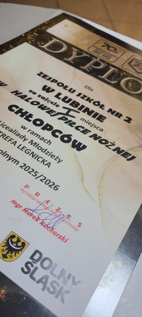 Zdjęcie dyplomu dla Zespołu Szkół nr 2 w Lubinie za zajęcie I miejsca w Halowej Piłce Nożnej Chłopców. Dyplom przyznany w ramach Licealiady Młodzieży – Strefa Legnicka w roku szkolnym 2025/2026. Na dole widoczny herb Dolnego Śląska oraz podpis prezesa Szkolnego Związku Sportowego