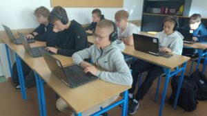 Uczniowie pracują przy komputerach przenośnych podczas zajęć informatycznych w pracowni komputerowej