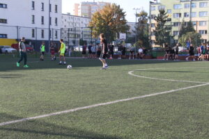 Uczniowie grający w piłkę nożną na szkolnym boisku wielofunkcyjnym podczas zajęć sportowych